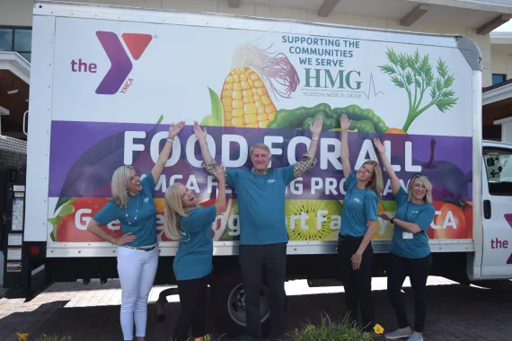 The Greater Kingsport Family YMCA staff and volunteers stand in front of a bus ready to deliver food to their community. 